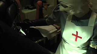 Rubbernurse Agnes, in her long grey latex dress and white surgery hood, gives a blowjob and prostate massage to the patient.