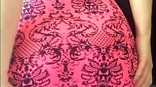 From behind, she masturbates in pink dress on bed