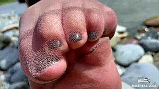 Goddess teases with tan nylons and cute soles by the river